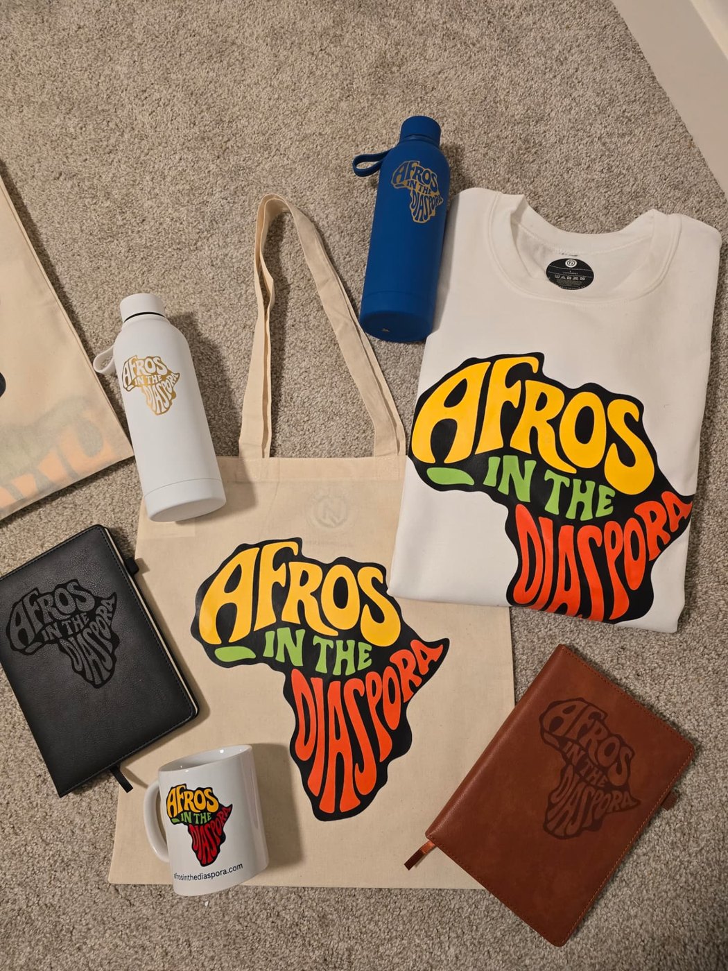 A full Art by Nuella product spread with printed apparel, drinkware, notebooks, tote bags and mugs